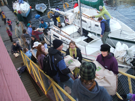 A chain of enthusiastic volunteers help unload grain from the sailboats docked in Nelson.