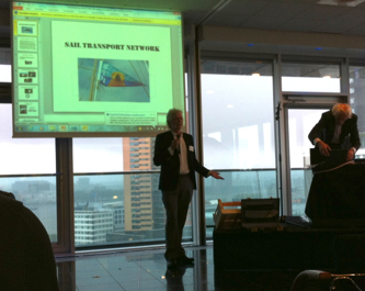 Jan Lundberg at SAIL Meeting, Sail Transport Network presentation. Burgee on screen.